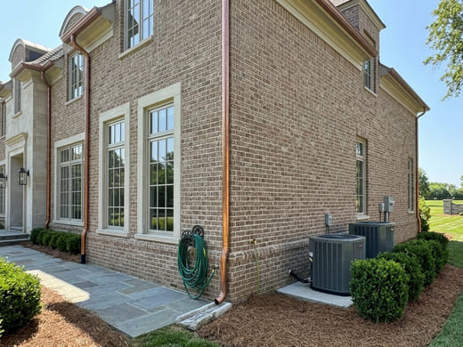 Exterior on a visit check: windows closed and intact, garden hose stowed, air-conditioning units clear of debris.
